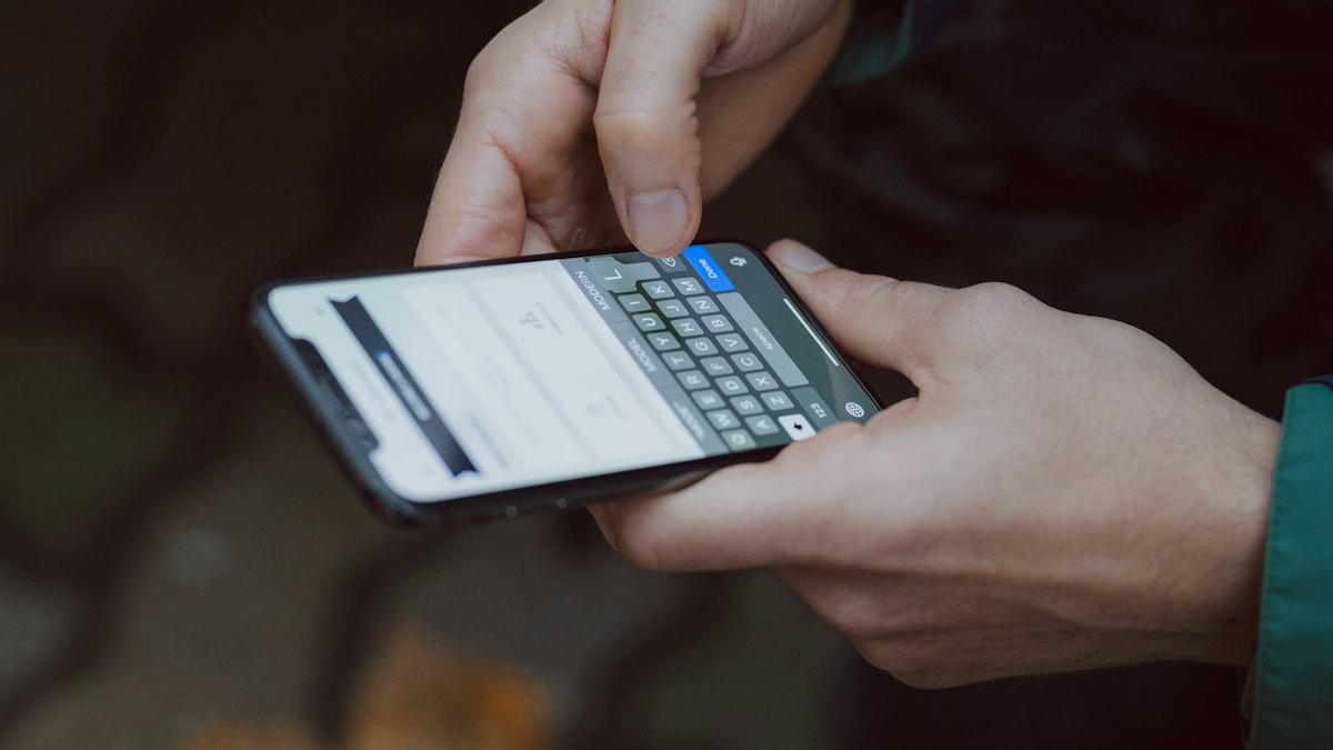 Close-up of hands typing a message on a smartphone keyboard